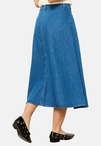 Blauwe denim midi-rok met een uitlopende A-lijn vorm, met een hoge taille, zijsplit en gestikte details. Draagt met zwarte platte schoenen.