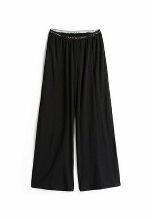 Zwarte wijde broek van zacht materiaal, met een elastische tailleband waarop de merknaam "Tommy Hilfiger" in het wit is gedrukt.