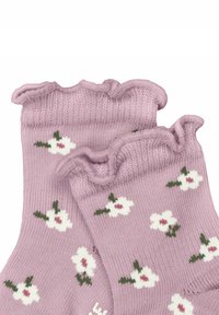 Lavendelfarbene Socken mit gerippten, rüschigen Bündchen, die kleine weiße Blumen mit rosa Mitte und grünen Blättern zeigen, gefertigt aus einem weichen Strickmaterial.