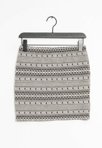 Schwarz-weiß gemusterter Rock mit geometrischen Designs, der horizontale Streifen und einen strukturierten Stoff aufweist. Hängt an einem schwarzen Kunststoffhaken.