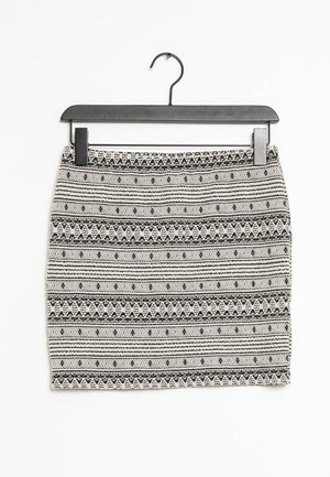 Czarna i biała spódnica w wzory geometryczne, z poziomymi paskami i teksturowanym materiałem. Wisząca na czarnym plastikowym haczyku.