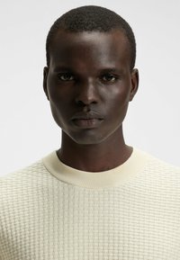 Maglione in cashmere leggero con texture, colletto a coste, caratterizzato da un motivo a scacchi e una silhouette aderente.