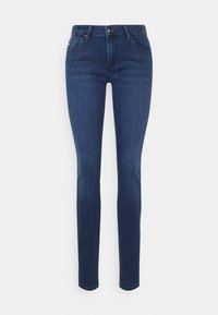 Jeans skinny em denim azul escuro, com uma cintura de altura média, bolsos frontais e um fecho com um único botão. Textura suave com desbotamento mínimo.