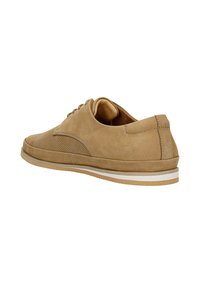 Chaussure en daim marron avec un design perforé, bout arrondi et semelle en caoutchouc blanche. Présente des lacets et un accent cousu sur le côté.
