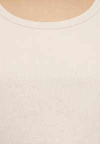 Jasno beżowy ribbed tank top o gładkiej fakturze i okrągłym dekolcie. Subtelny efekt połysku na całej tkaninie.