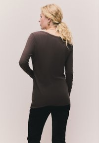 Rudas ilgomis rankovėmis, su briaunomis, marškinėliai su apvaliu iškirpimu, derinami su juodomis kelnėmis. Lygus tekstūros ir aptemptas dizainas.