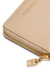 Beige leather wallet with gold-tone hardware, zip closure, and a textured fabric section. Embossed logo on the surface.