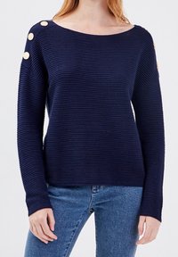 Námořnický svetr z žebrovaného úpletu s širokým výstřihem a dekorativními zlatými knoflíky na rameni. Dlouhé rukávy a volný střih.