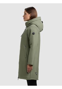 Parka verde con cappuccio, dotata di chiusura con zip, tasche laterali e patch con logo sulla manica. Tessuto liscio e resistente all'acqua.