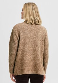 Langärmliger, oversized Pullover in Hellbraun, aus strukturiertem Strickstoff mit lockerer Passform und überschnittenen Schultern.