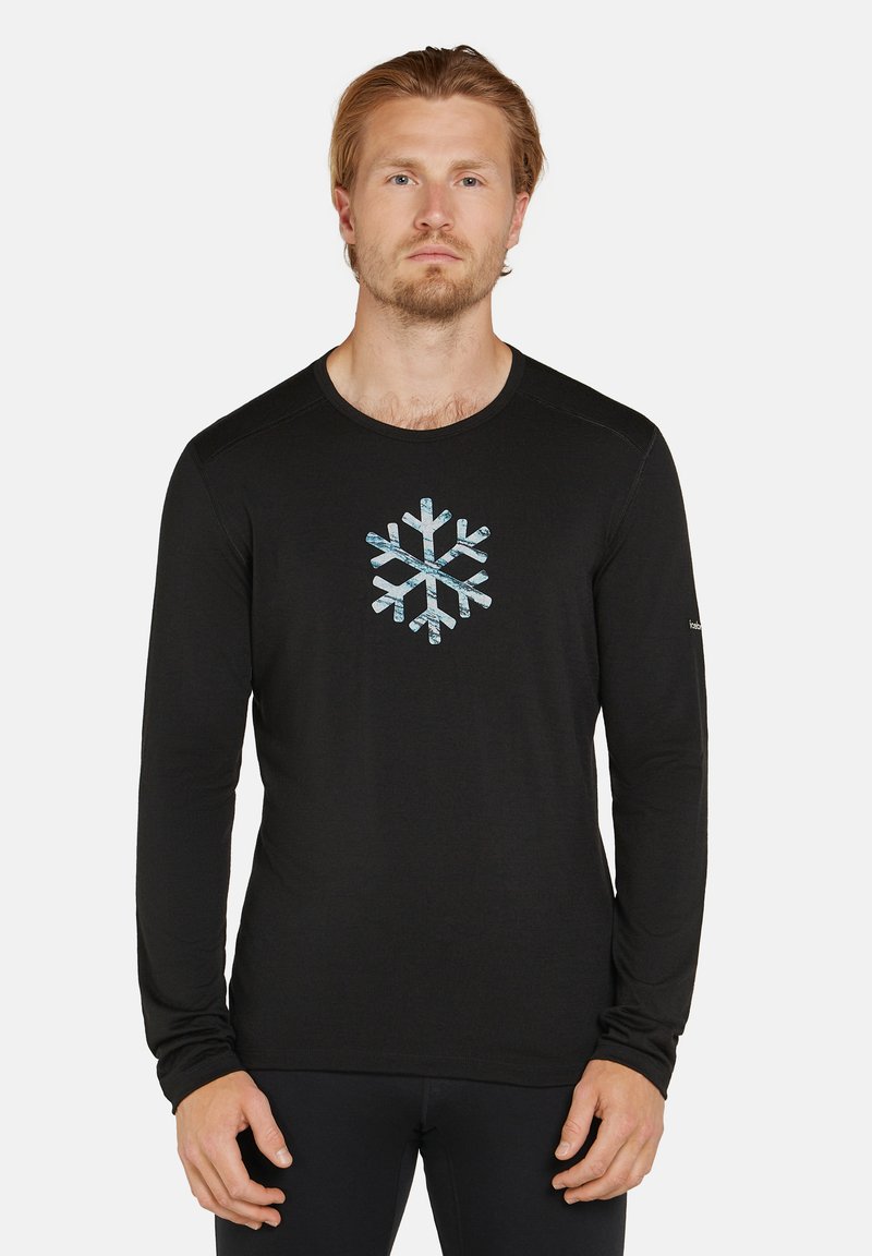 Svart långärmad tröja med ett blått och vitt snöflinge-mönster i mitten. Gjord av ett mjukt, lätt tyg.