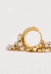 Zlaté kruhové náušnice s hladkým povrchom, ktoré obsahujú zhluk čírych kamienkov a štvorcové kovové akcenty, prepletené s prepojeným reťazcom.