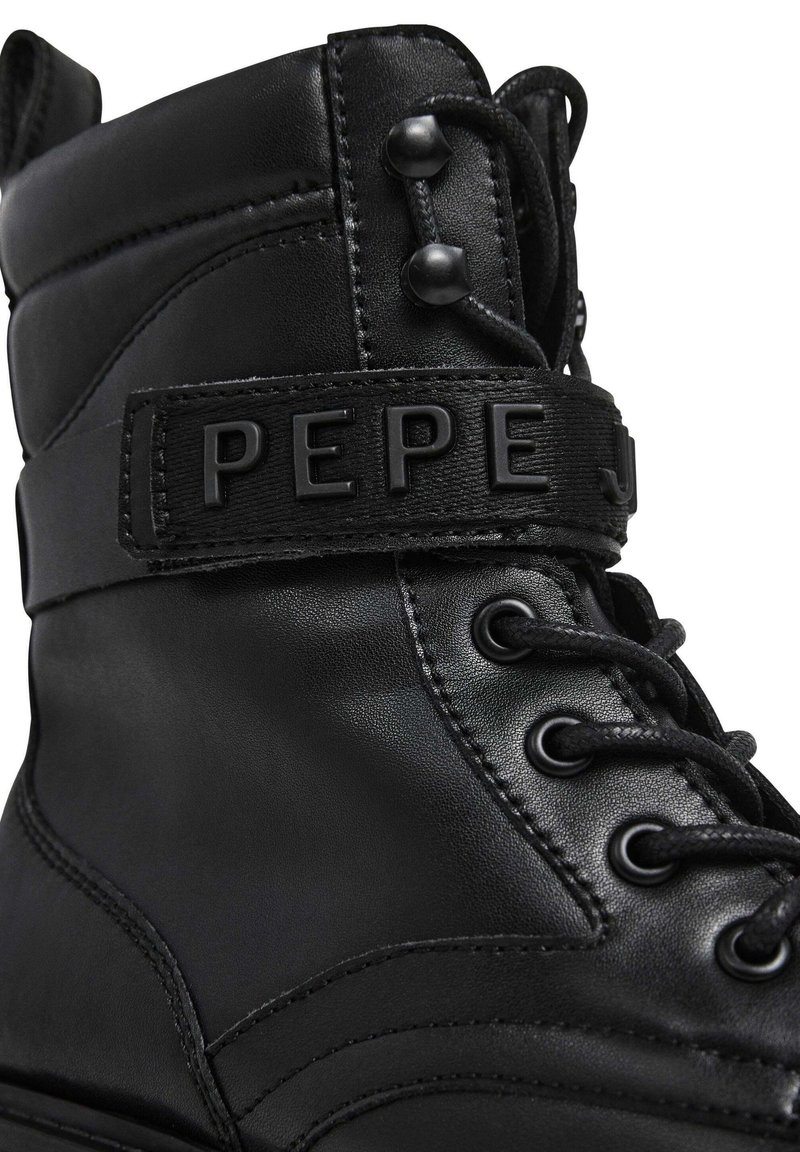 Botas de tobillo de cuero negro con un collar acolchado, cordones redondos y una correa de marca prominente que dice "PEPE". Presenta una superficie texturizada y costuras mínimas.