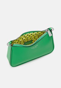 Wristlet verde Kate Spade con zip argentata, etichetta con logo e fodera interna gialla a motivo con slot per carte.
