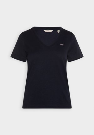 Námořnická modrá V-krční tričko vyrobené z měkké bavlny. Krátké rukávy s malým vyšitým logem na levé hrudi. Jednoduchý, minimalistický design.