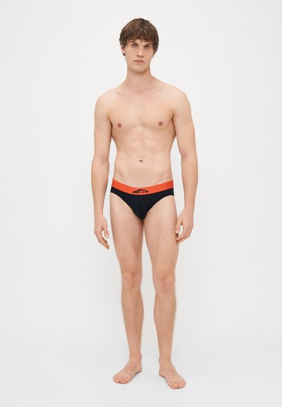 Ανδρικά μαγιό σε μαύρο χρώμα με αντίθετη πορτοκαλί ζώνη. Διαθέτει λογότυπο στη ζώνη, λεία υφή και σταθερά εφαρμοστό σχέδιο.