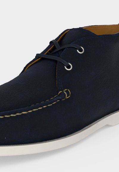Navy blue leather casual lace-up shoe with white sole and contrast stitching along moc toe and sides.