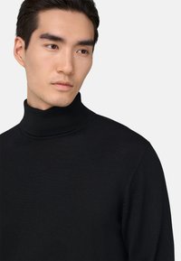 Černý rolák vyrobený z žebrované látky, který má těsný střih a vysoký límec, zobrazený na jednobarevném světlém pozadí.