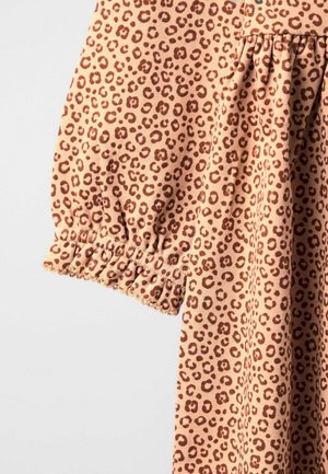 Beige Stoff mit braunem Leopardenmuster, ausgestattet mit einem gerafften elastischen Bündchen und einer Naht mit Rüschendetails.