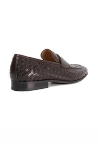 Brown woven leather loafers with a low heel, featuring a rounded toe and a decorative strap across the front. Textured pattern throughout.