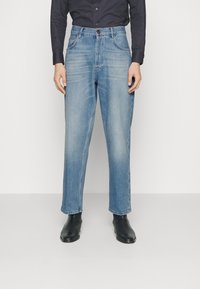 Ljusblå denimjeans med rak skärning, med knappstängning, fem fickor och subtila blekningar. Bärs med svarta ankelboots.