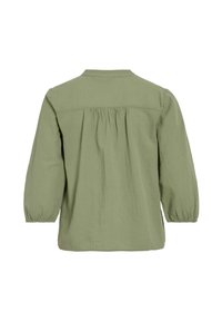 Blusa verde, leggera, a maniche lunghe con dettaglio plissettato sulla schiena e colletto con bottoni. Tessuto morbido, vestibilità rilassata e maniche arricciate.