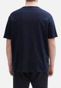 T-shirt en coton bleu marine, à manches courtes, col ras du cou, design uni. Vue de l'arrière, montrant une coupe décontractée et une texture lisse.