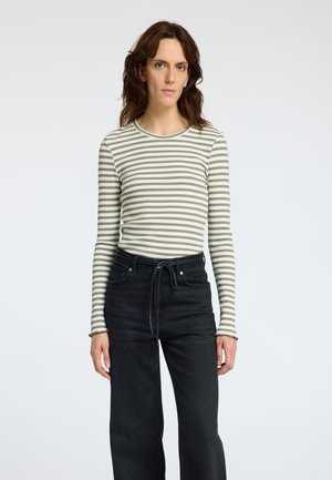Haut à manches longues rayé en vert clair et crème, texture côtelée. Assorti à un pantalon noir taille haute avec passants de ceinture et cordon de serrage.