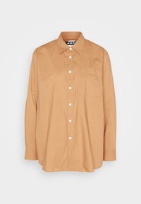 Camicia in cotone a maniche lunghe, con bottoni, di colore beige chiaro, dotata di taschino sul petto, bottoni bianchi e design con colletto classico.