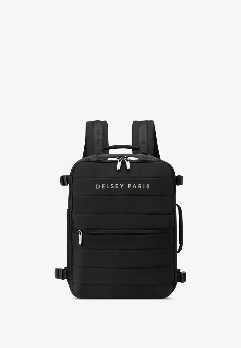 Mochila negra con textura acolchada, correas ajustables, asa superior y acentos de hardware plateado. Logo "DELCY PARIS" mostrado en la parte frontal.