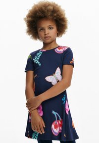 Abito blu navy a maniche corte con motivi colorati di farfalle, ciliegie e fiori, caratterizzato da un orlo curvo e dettagli testuali in colori vivaci.