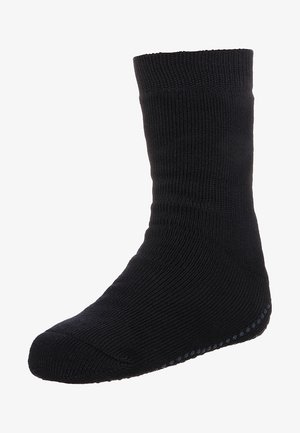 Schwarze gestrickte Socke mit geripptem Muster, hohem Knöchel und rutschfesten Gummielementen an der Sohle für besseren Halt.