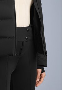 Crni podstavljeni jakna sa zatvaračem, nosi se preko kreme topa s rebrastim uzorkom i crnih tajica visokog struka. Sadrži vidljive dugmadi i šavove.