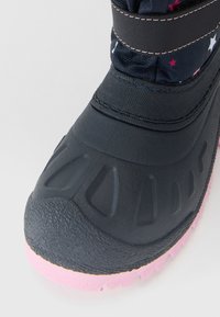 Schwarze wasserdichte Kinderstiefel mit pinker Sohle, Obermaterial aus Stoff, verziert mit weißen und pinken Sternen, und einem Klettverschluss.