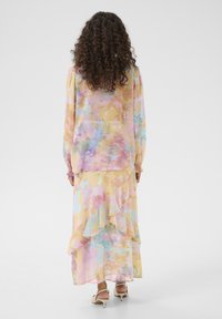 Abito lungo multicolore con orlo a volant, caratterizzato da toni di giallo pastello, rosa e blu. Realizzato in un tessuto morbido e con maniche lunghe.