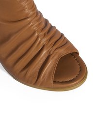 Braune Leder-Sandale mit geraffter Textur, offener Zehenpartie und gestickten Akzenten. Die Sohle ist flach und leicht gerundet.