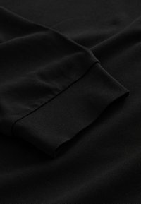 Black long-sleeve shirt with a textured knit fabric. The sleeve features a cuff design, providing a snug fit at the wrist.