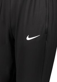 Pantaloni atletici neri realizzati in tessuto leggero, con logo Nike bianco sulla gamba sinistra. Texture liscia e design con cintura elastica.