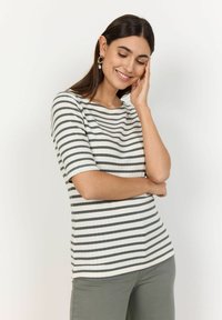 Gestreiftes Kurzarmoberteil in Weiß und Grau, mit gerippter Textur und einem Bootsausschnitt, kombiniert mit olivgrünen Hosen.