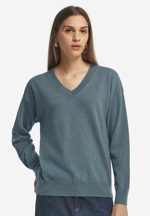 V-Ausschnitt-Pullover aus weichem, meliertem Teal-Stoff. Verfügt über lange Ärmel, gerippte Bündchen und Saum, einen lässigen Schnitt und eine glatte Textur.