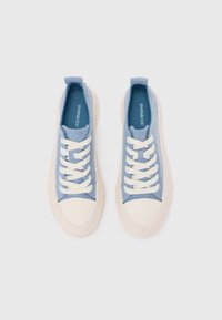 Light blue canvas sneakers with white laces and cream rubber soles, featuring a rounded toe and contrasting textured accents on the sides.