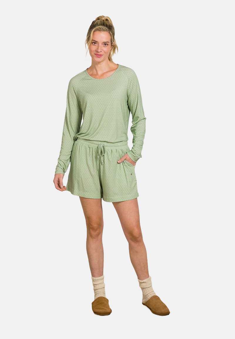 Hellgrünes Schlafanzug-Set mit Longsleeve-Oberteil und Shorts mit Kordelzug. Zarte strukturierte Muster, kombiniert mit braunen Hausschuhen und cremefarbenen Socken.