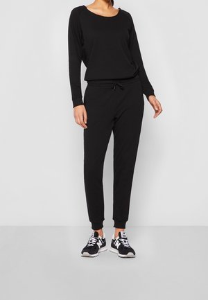 Haut noir à manches longues avec un col arrondi, associé à un pantalon jogger noir fuselé avec une taille élastique et un cordon de serrage.