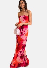 Robe maxi sans bretelles dans des teintes vives de rose et de rouge avec un motif floral abstrait. Présente une silhouette ajustée et une texture lisse.