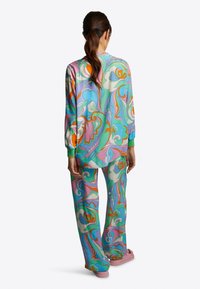 Färggs loungewear-set bestående av en mönstrad långärmad topp och matchande byxor, tillverkade av ett mjukt material i pastellfärger med virvlar.