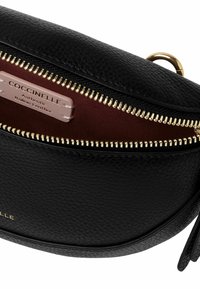 Borsa a tracolla in pelle nera con superficie testurizzata, zip dorata e fodera bordeaux con etichetta che indica pelle italiana autentica.