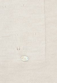 Suéter de punto texturizado beige que presenta un panel liso y una etiqueta ovalada metálica con detalle en relieve. Acentos de costura sutiles en toda la prenda.