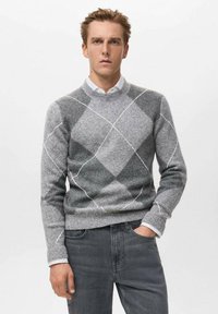 Suéter de lana gris con un patrón de diamantes en diferentes tonos de gris y blanco, cuello redondo y puños acanalados, combinado con jeans grises.