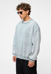 Lichtblauwe oversized sweatshirt met ribgebreide cuffs en onderrand, met een subtiele logo op de voorkant. Soepele katoenmix stof.