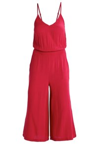 Mono rojo con tirantes finos, escote en v y textura plisada. El diseño de pierna ancha cae por debajo de la rodilla, con una cintura elástica.